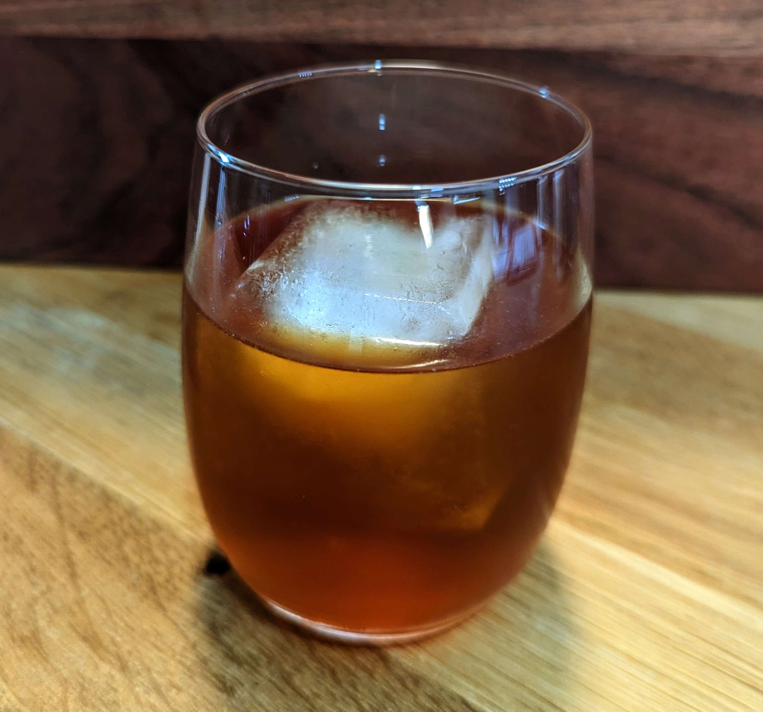 A cold glass of light-brown coffee tonic, with ice.